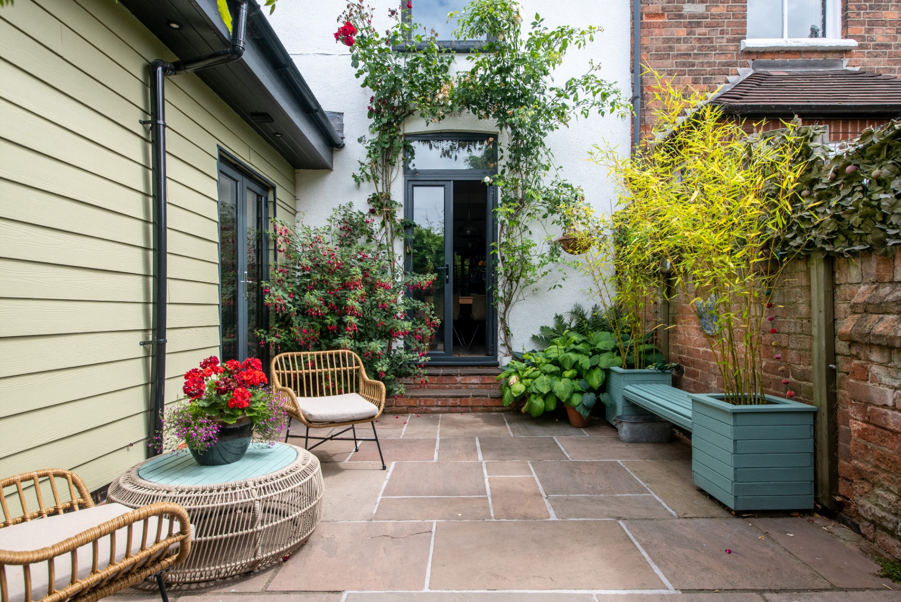 Finished patio with painted timber planters, climbing rose and seating