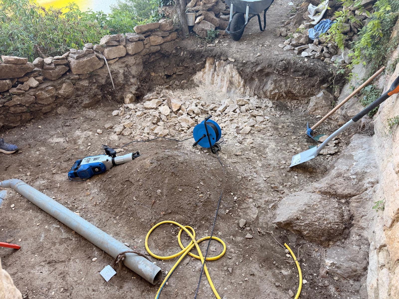 Excavated patio area with rubble and damaged stone wall before the rescue works in La Roque-Gageac