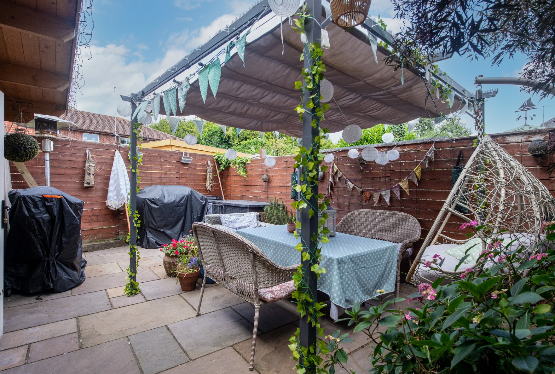 Finished courtyard with steel pergola, fabric canopy, lanterns and rattan seating