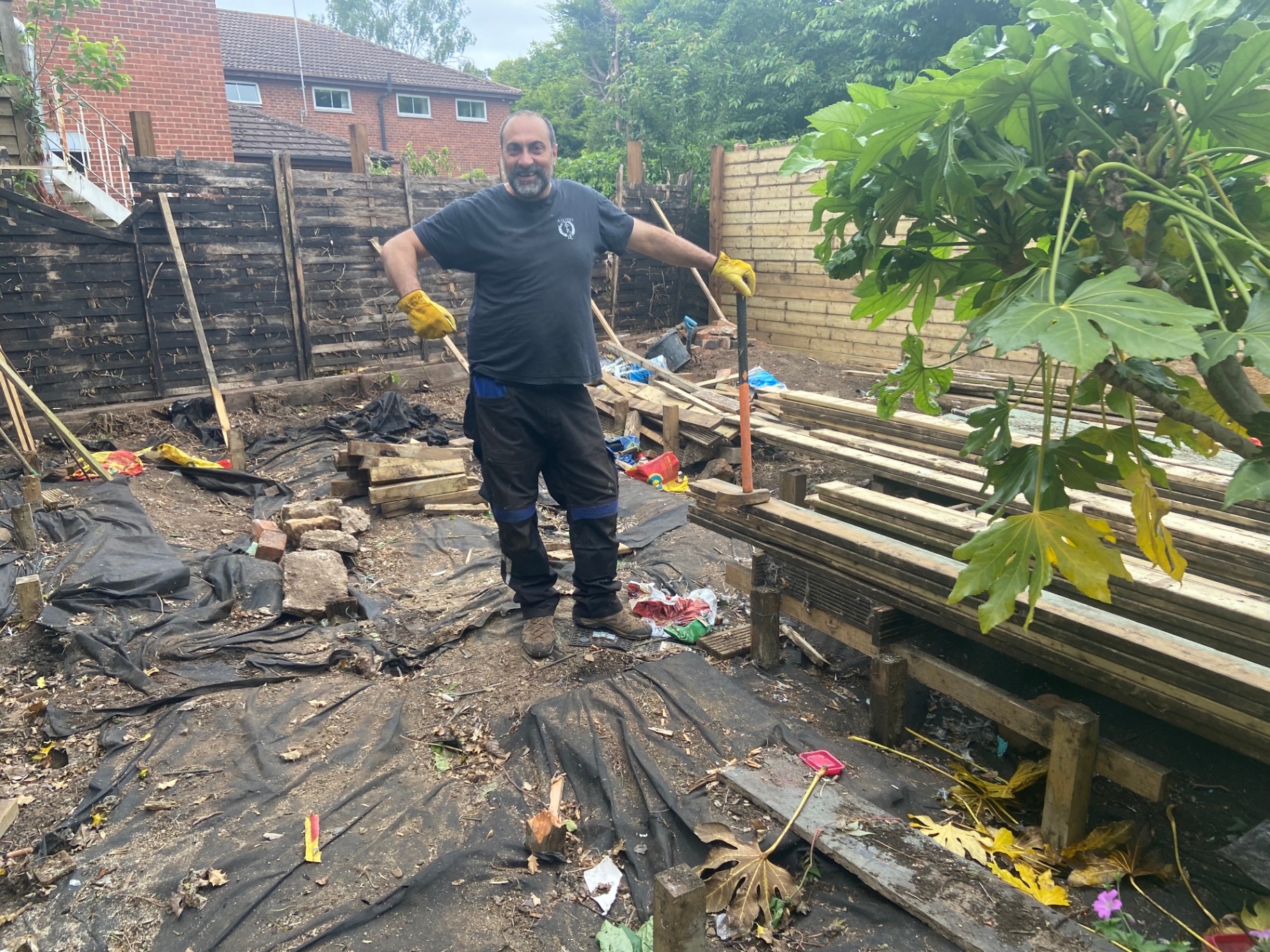 Jose clearing the courtyard with gloves and shovel during the strip-out